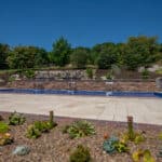 outdoor living space with in ground swimming pool, water falls, water feature, patio, pavers, pavilion, fire pit, natural stone stairs, and retaining walls