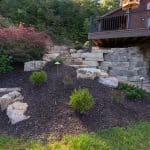 large retaining wall with landscaping and natural stone stairs