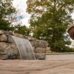 retaining wall near fiberglass swimming pool with spillway leading to pool