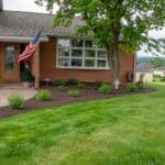 outdoor lighting in mulch bed with plantings with paver side walk and pillar