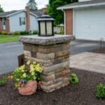 outdoor lighting in mulch bed with plantings with paver side walk and pillar