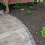 outdoor lighting in mulch bed with plantings and paver sidewalk