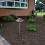 outdoor lighting in mulch bed with plantings with paver side walk