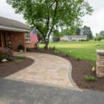 outdoor lighting in mulch bed with plantings with paver side walk