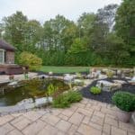 Outdoor living space with patio, pavilion, pond, and landscaping