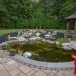 Outdoor living space with patio, pavilion, pond, and landscaping