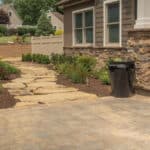 mulch planting bed with flagstone walk way and water feature with stacked slate urn waterfall and paver driveway