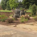 mulch planting bed with flagstone walk way and water feature with stacked slate urn waterfall