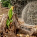 stacked slate urn water feature with mountain boulders and landscaping and driftwood