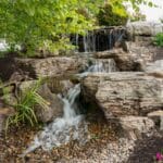 water feature with waterfall, mountain boulders, and landscaping