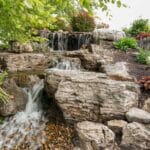 water feature with waterfall, mountain boulders, and landscaping
