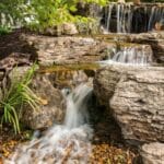 water feature with waterfall, mountain boulders, and landscaping