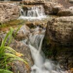 water feature with waterfall, mountain boulders, and landscaping