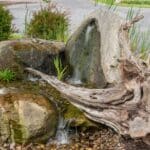 water feature with waterfall, mountain boulders, and landscaping