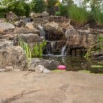 water feature with waterfall, mountain boulders, and landscaping