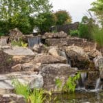 water feature with waterfall, mountain boulders, and landscaping