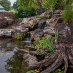 water feature with waterfall, mountain boulders, and landscaping
