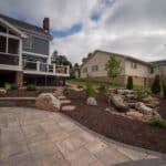 outdoor living space with paver patio, firepit, natural stepping stones, mulch planting beds, and landscaping