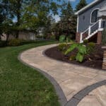 paver sidewalk with landscaping and stone pillar