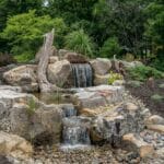 water feature with waterfall, mountain boulders, and landscaping