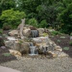 water feature with waterfall, mountain boulders, and landscaping