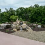 water feature with waterfall, mountain boulders, and landscaping