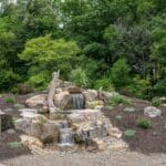 water feature with waterfall, mountain boulders, and landscaping