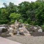 water feature with waterfall, mountain boulders, and landscaping