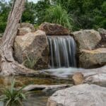 water feature with waterfall, mountain boulders, and landscaping