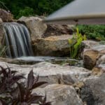 water feature with waterfall, mountain boulders, and landscaping