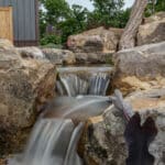 water feature with waterfall, mountain boulders, and landscaping