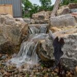 water feature with waterfall, mountain boulders, and landscaping