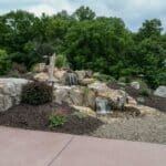 water feature with waterfall, mountain boulders, and landscaping