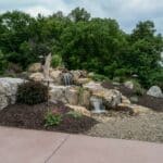 water feature with waterfall, mountain boulders, and landscaping