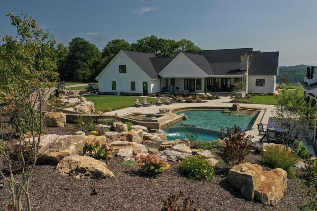 Outdoor living space with swim rec pond, paver patio, landscaping, and mountain boulders