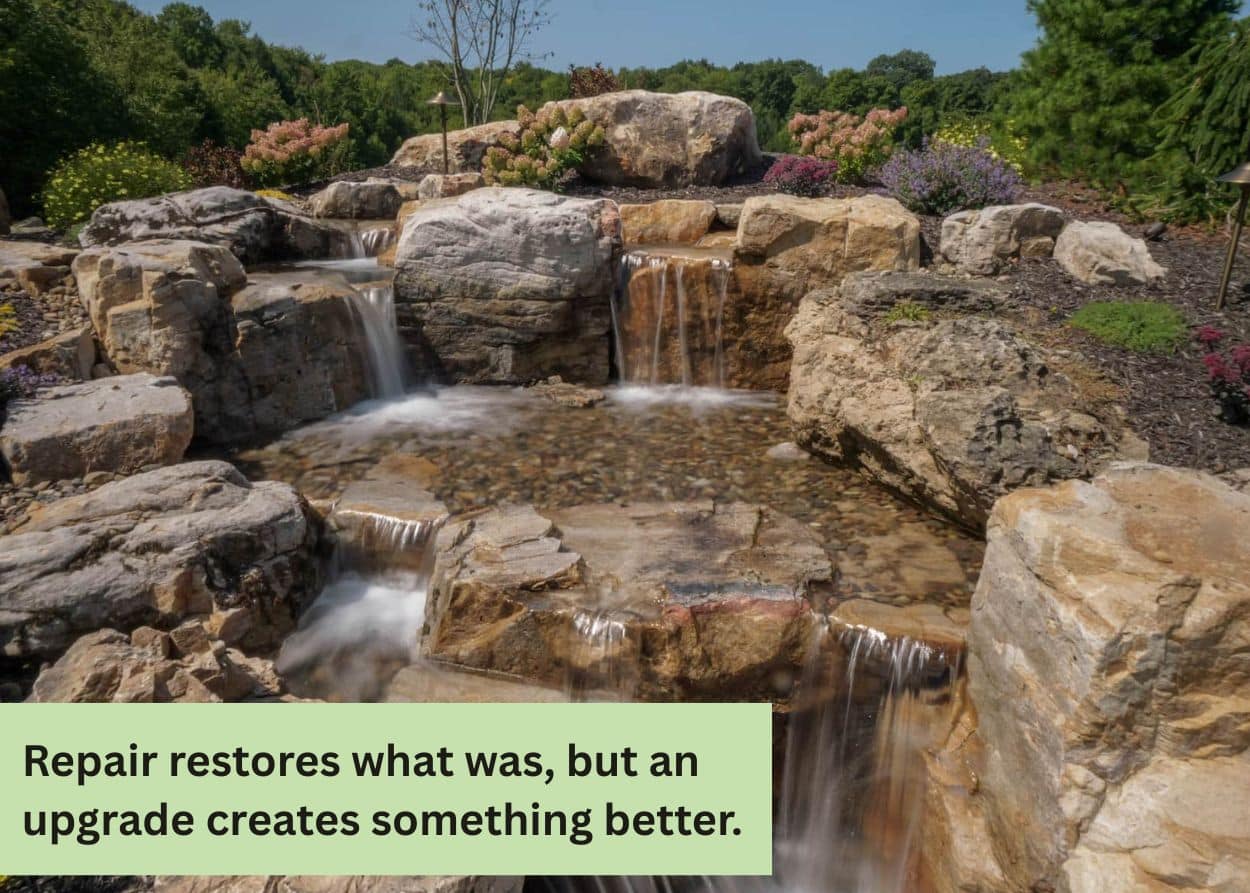 Multi-level backyard pond with cascading waterfalls and natural boulders in a Central Pennsylvania landscape.