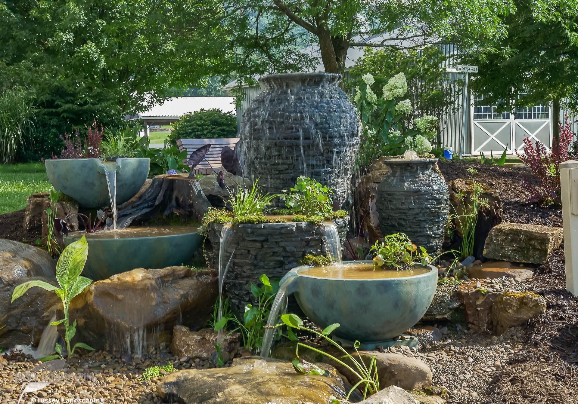 A water feature in a backyard with rocks and pots.