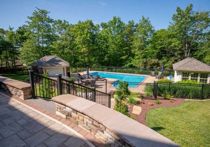 outdoor living space with pool, paver patio, natural stone stairs, and landscaping