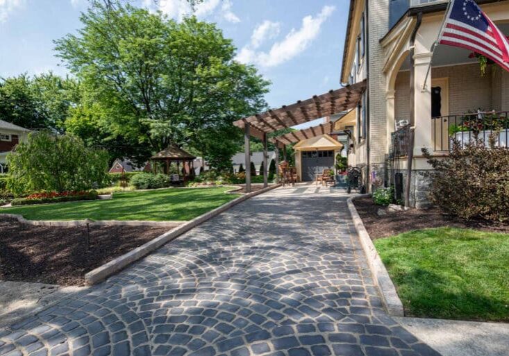 paver sidewalk with pergola and landscaping and edging fish scale driveway