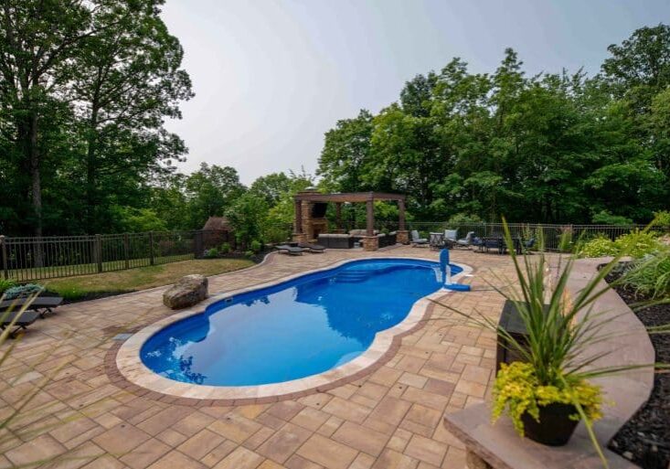 outdoor living space with fiberglass swimming pool, pergola, and paver patio