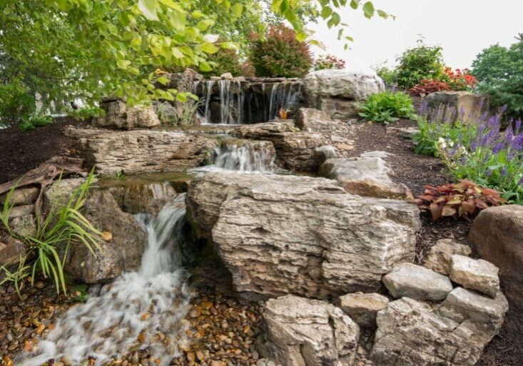 water feature with waterfall, mountain boulders, and landscaping