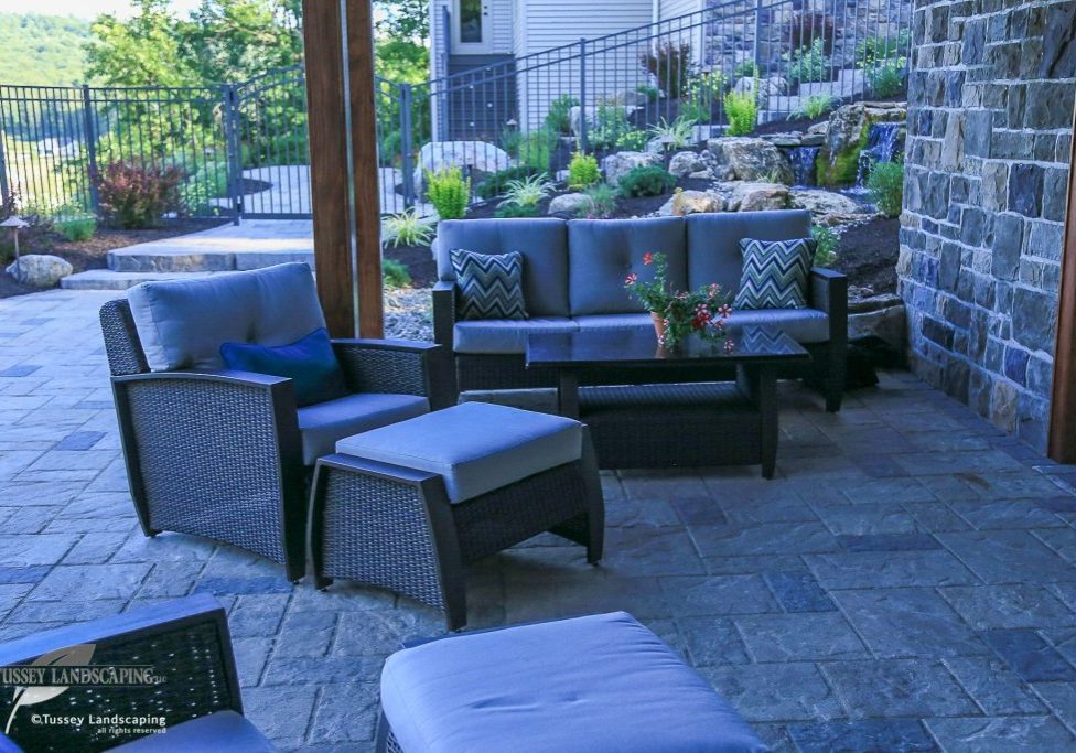 A patio with patio furniture and a stone wall.