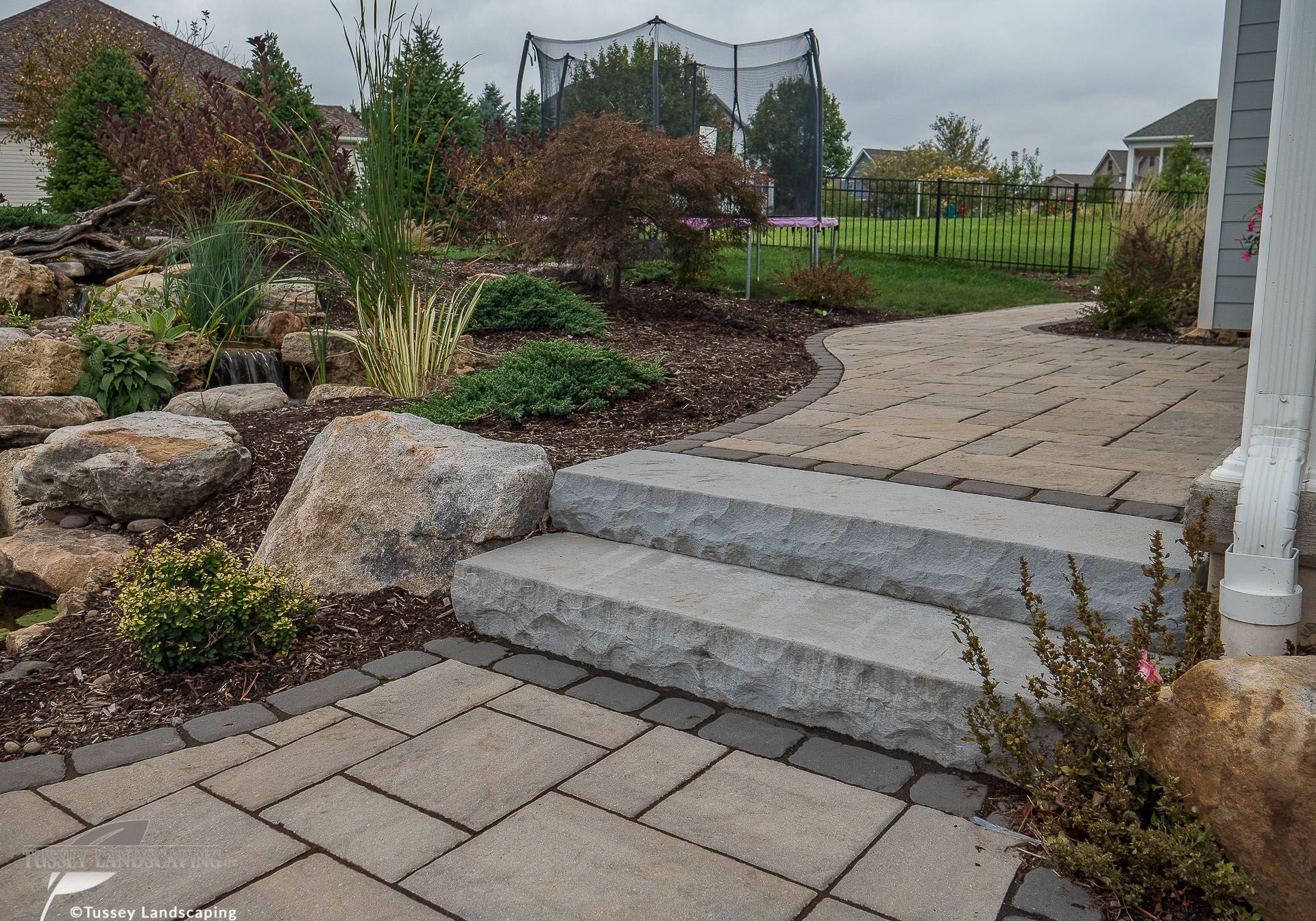 A stone walkway leading to a backyard.