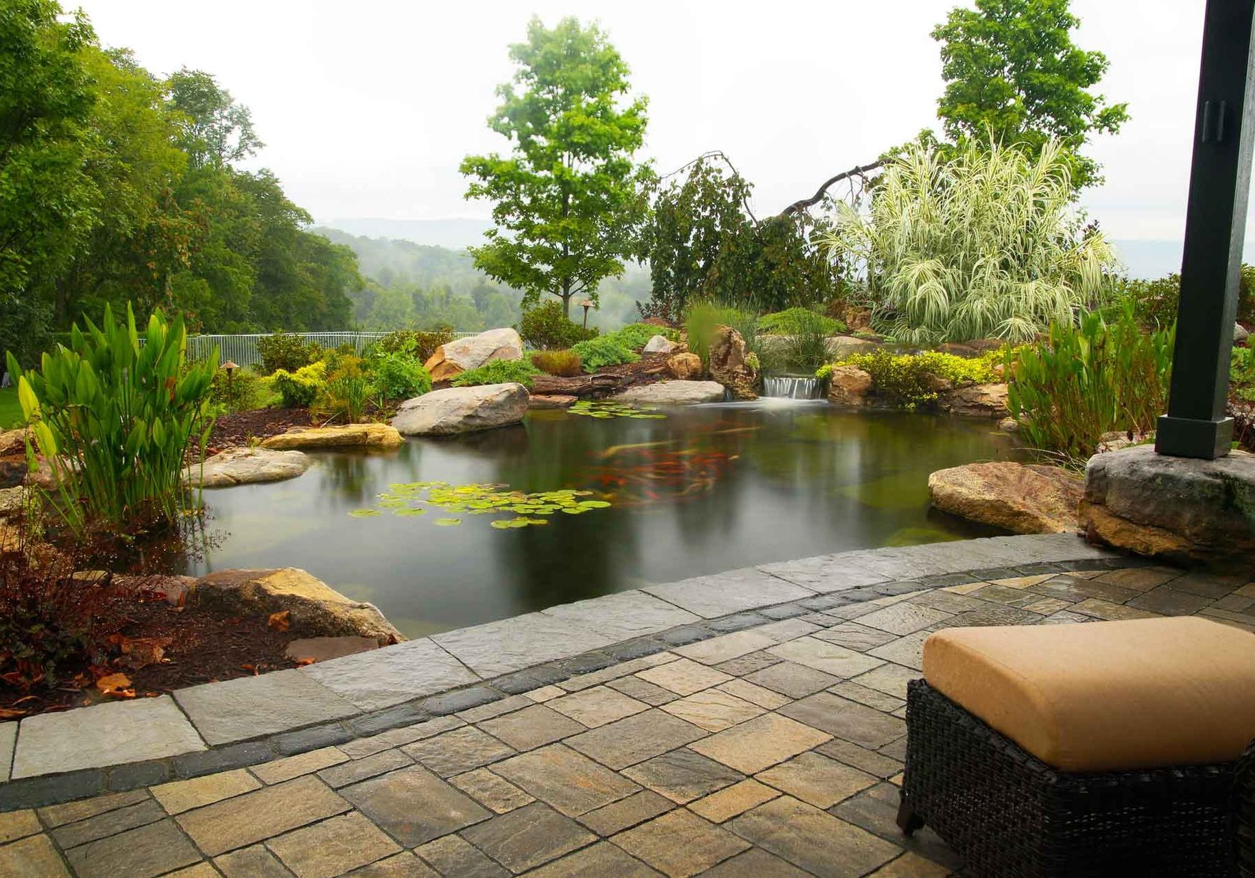 A backyard with a pond and patio furniture.