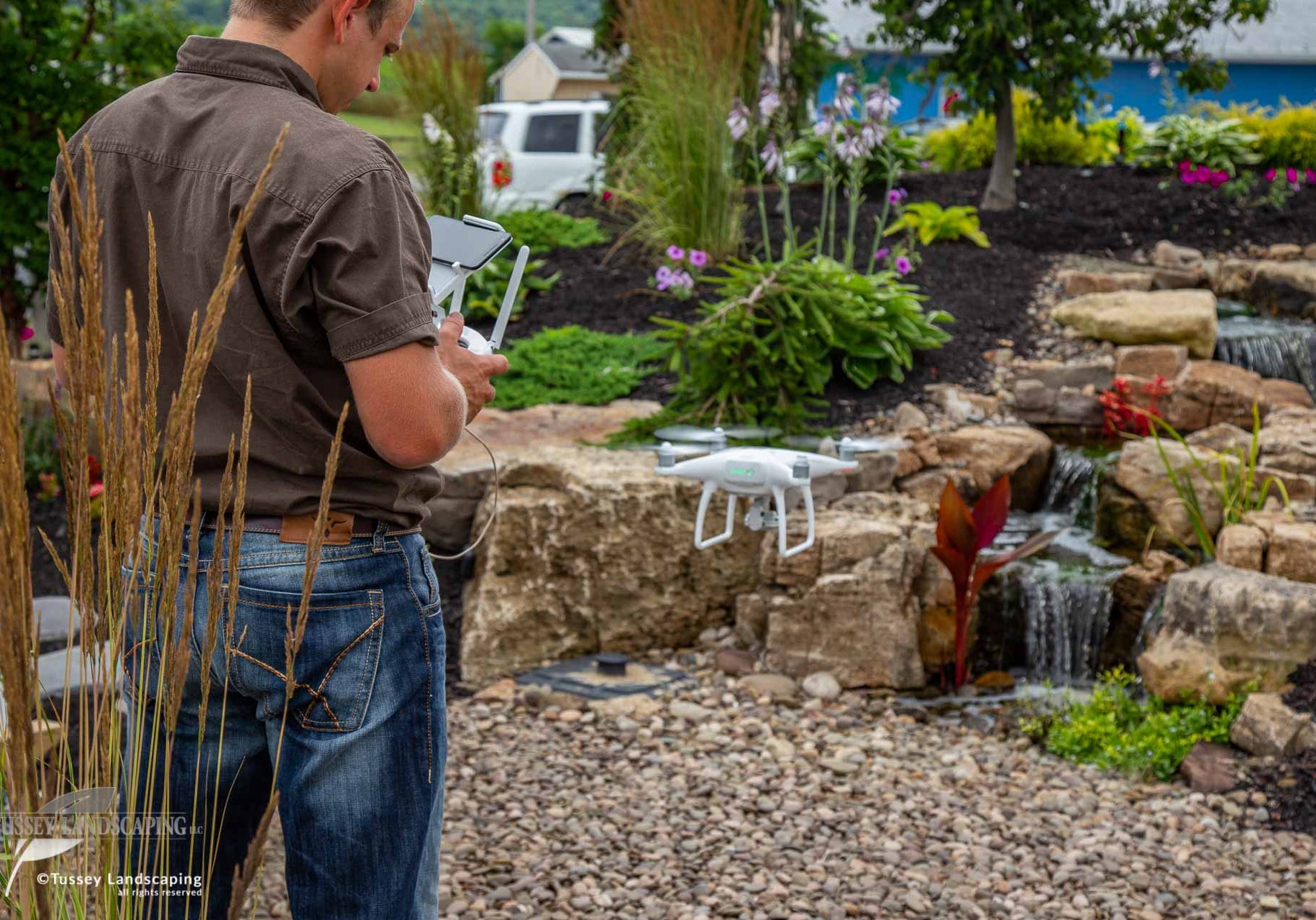 A man holding a drone in front of a waterfall.