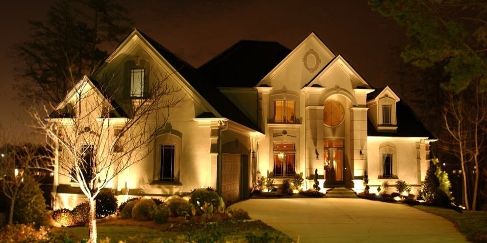 A home is lit up at night with landscape lighting.