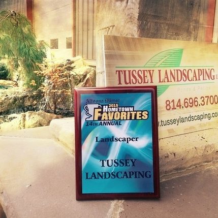 A sign for tussy landscaping in front of a house.