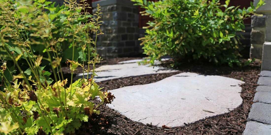 In Need Of a Landscape Contractor? A walkway with stones and plants in front of a house.