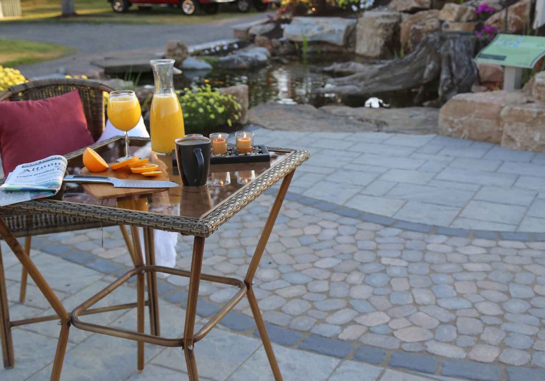 A patio with a table and chairs and a pond.