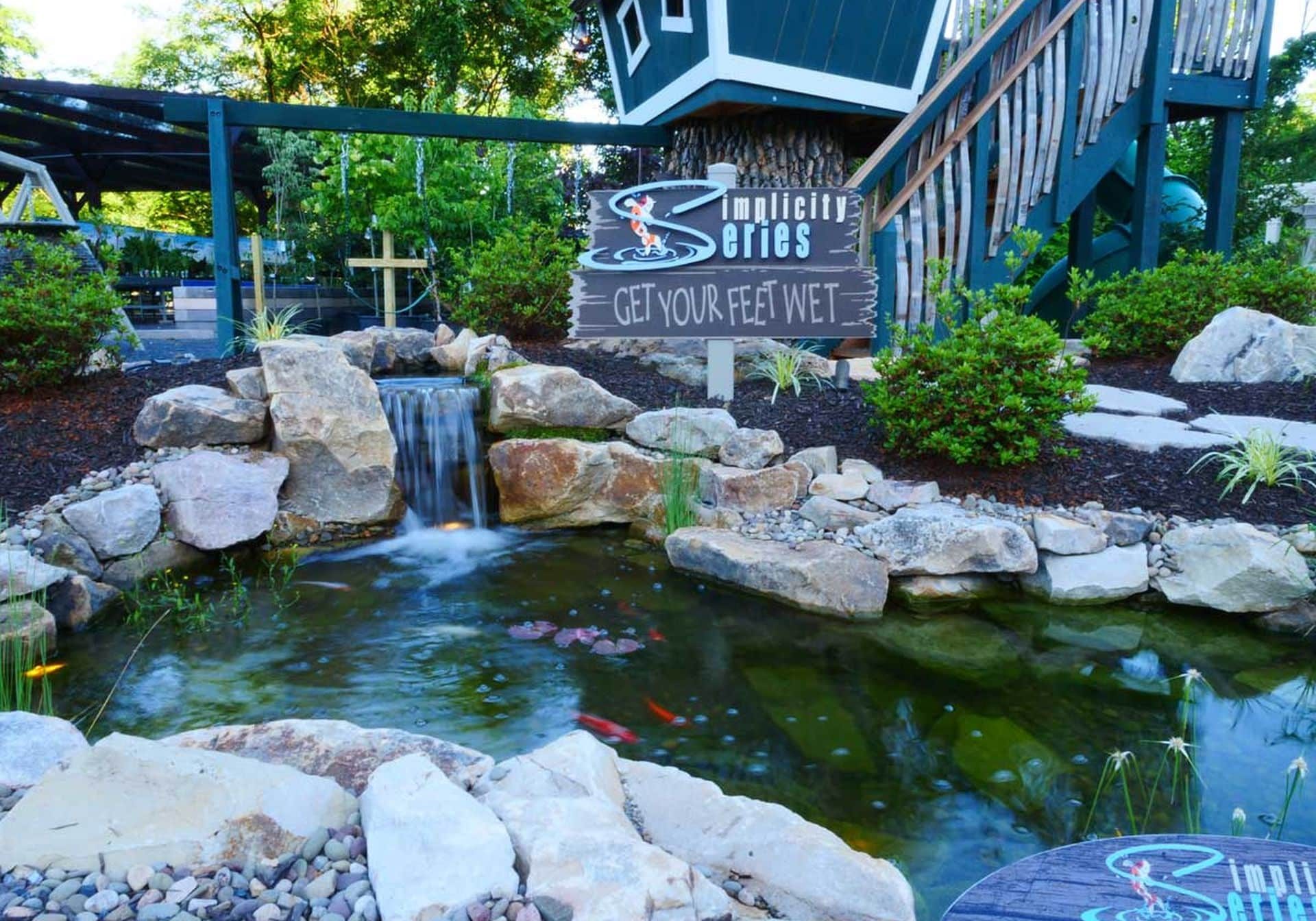 A small pond with a waterfall and a sign.